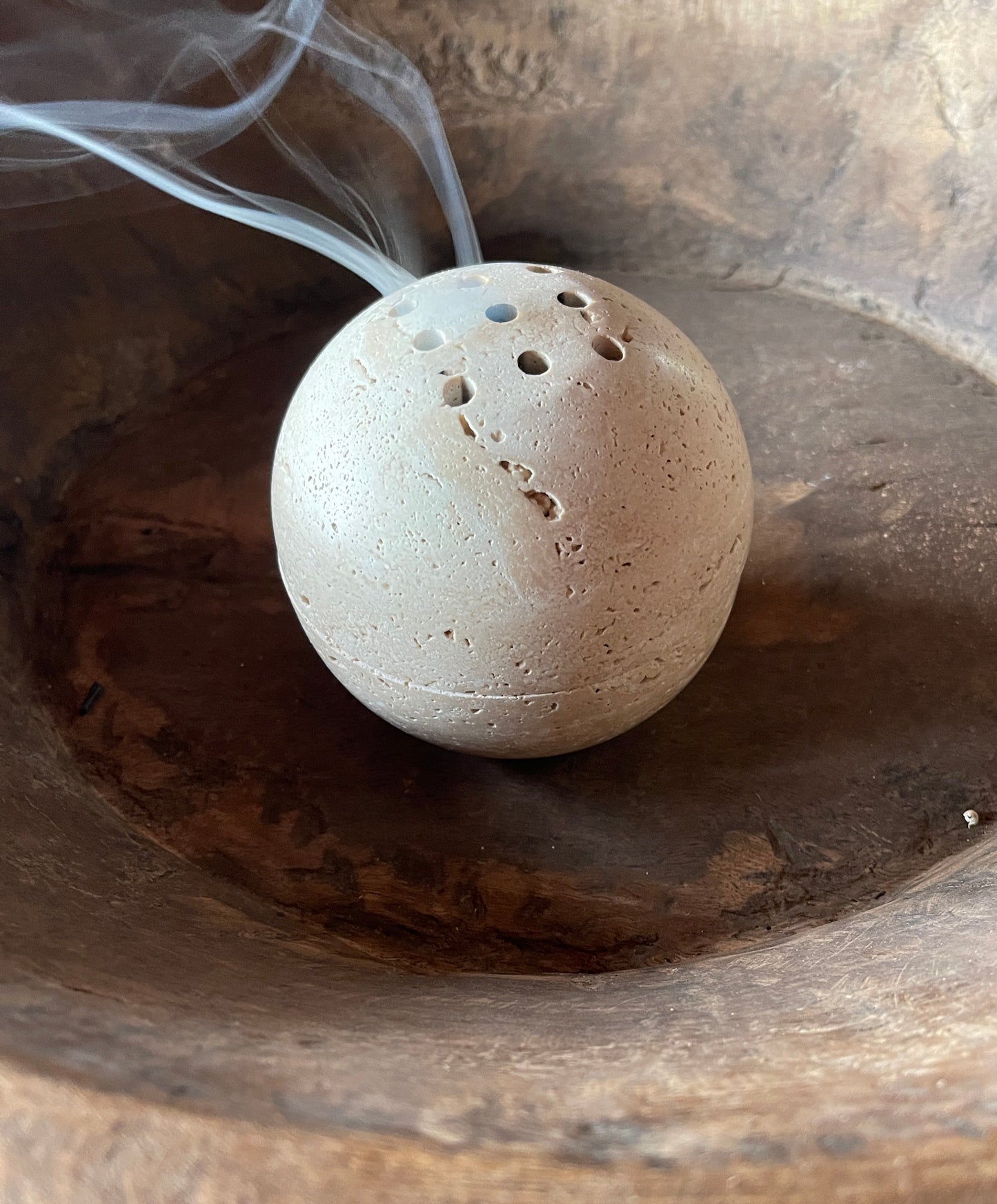 Round stone-like object with small holes on a wooden surface