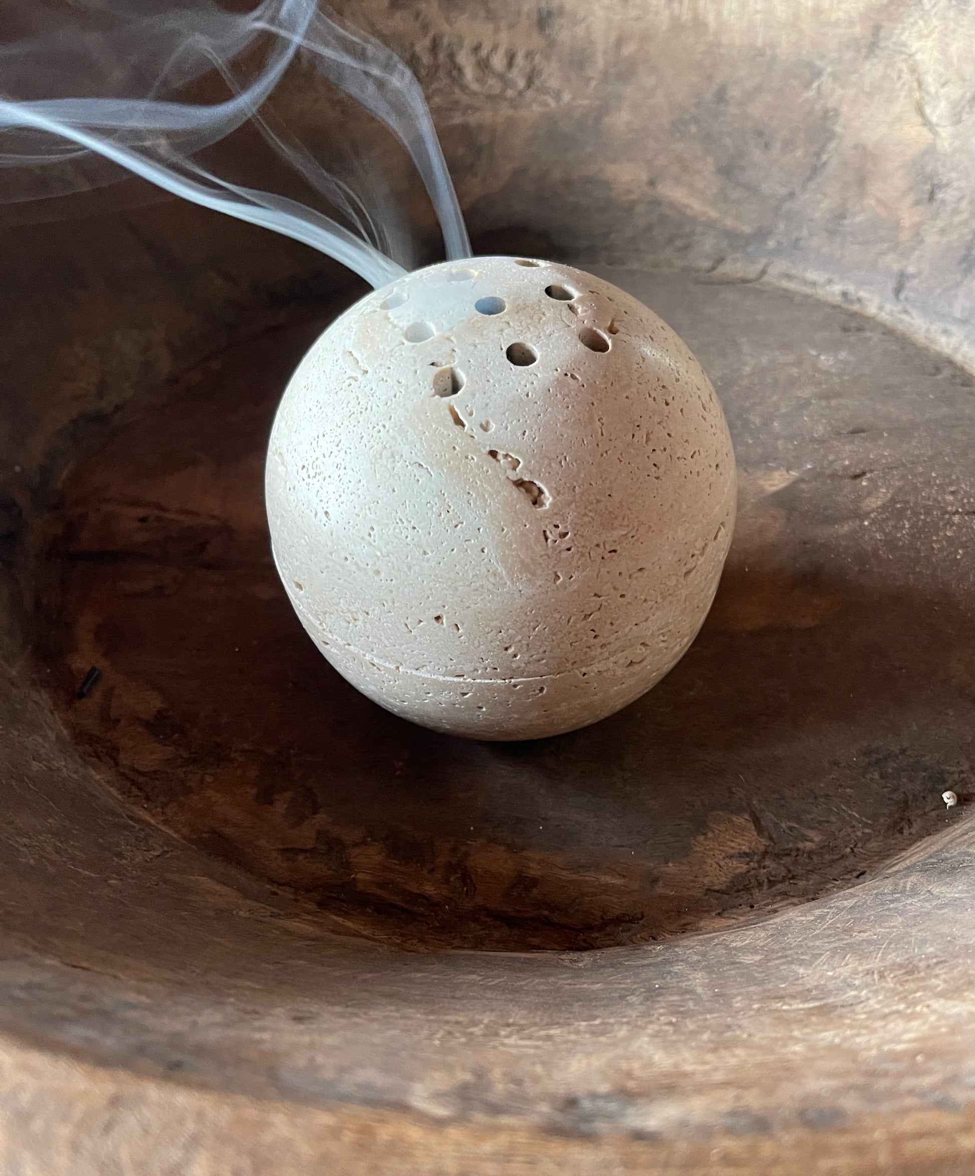 Round stone-like object with small holes on a wooden surface