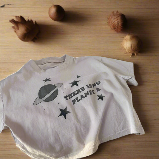 Beige t-shirt with space-themed design on a beige couch with polka dot socks.