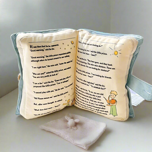 Decorative pillow with book design on a surface near a window